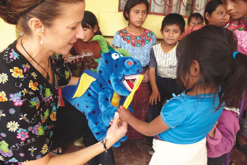 group of kids learning how to brush teeth with a stuffed animal