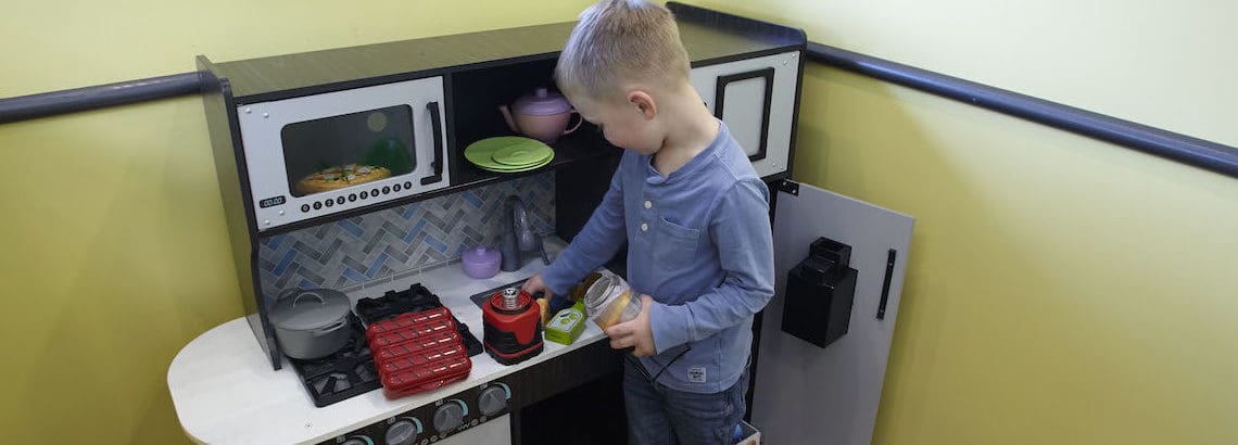 young boy playing with bbq camping toys in dental office